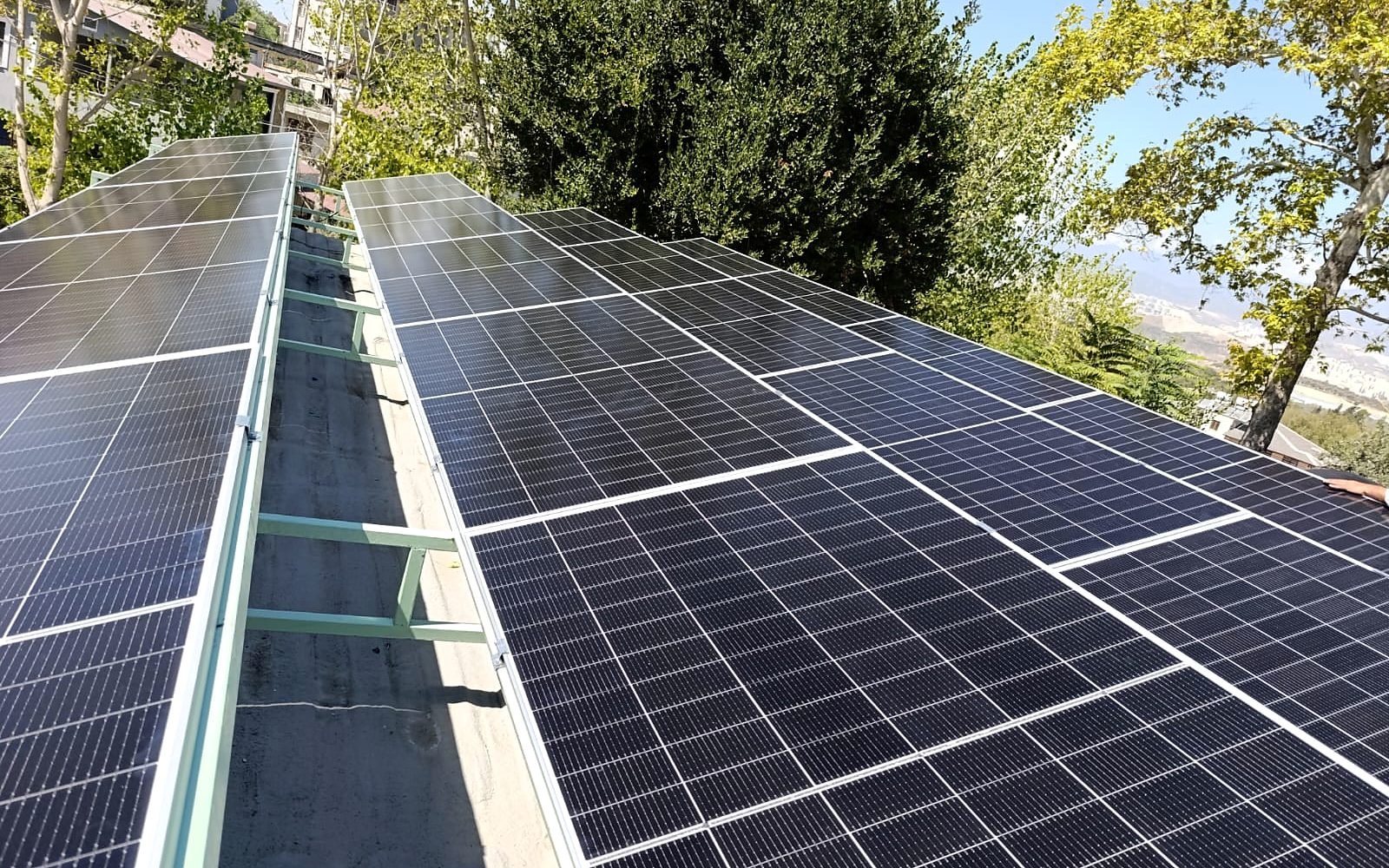 Says Enerji tarafından kurulan çatı üstü güneş enerjisi sistemi, arkada Hatay dağları